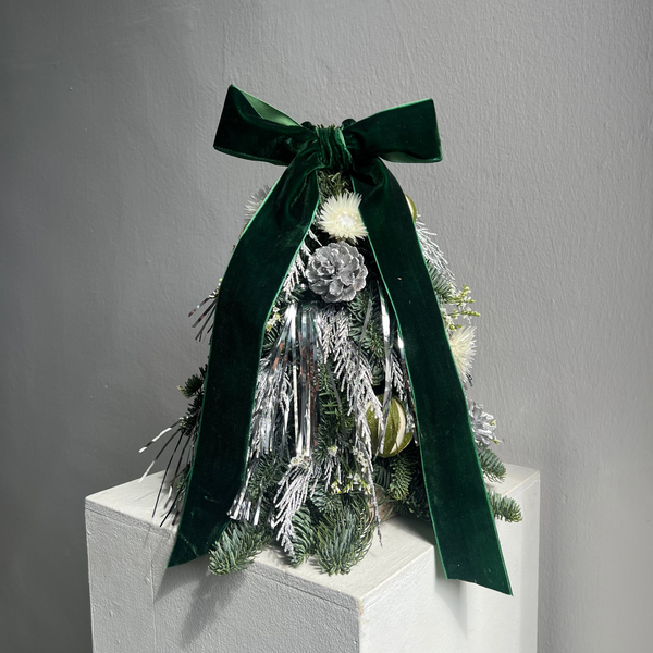 Decorative Christmas tree with green ribbon on a gray background