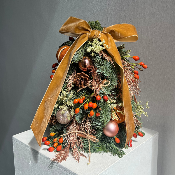 Decorative Christmas tree with a large brown bow on a gray background