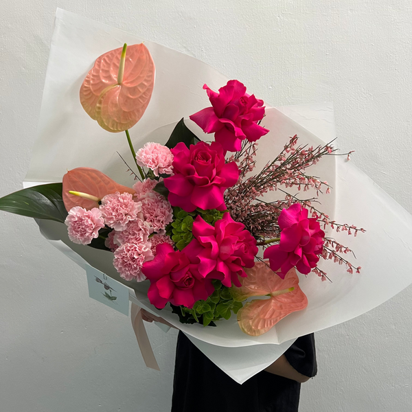 Bouquet of pink and red flowers with greenery on a plain background
